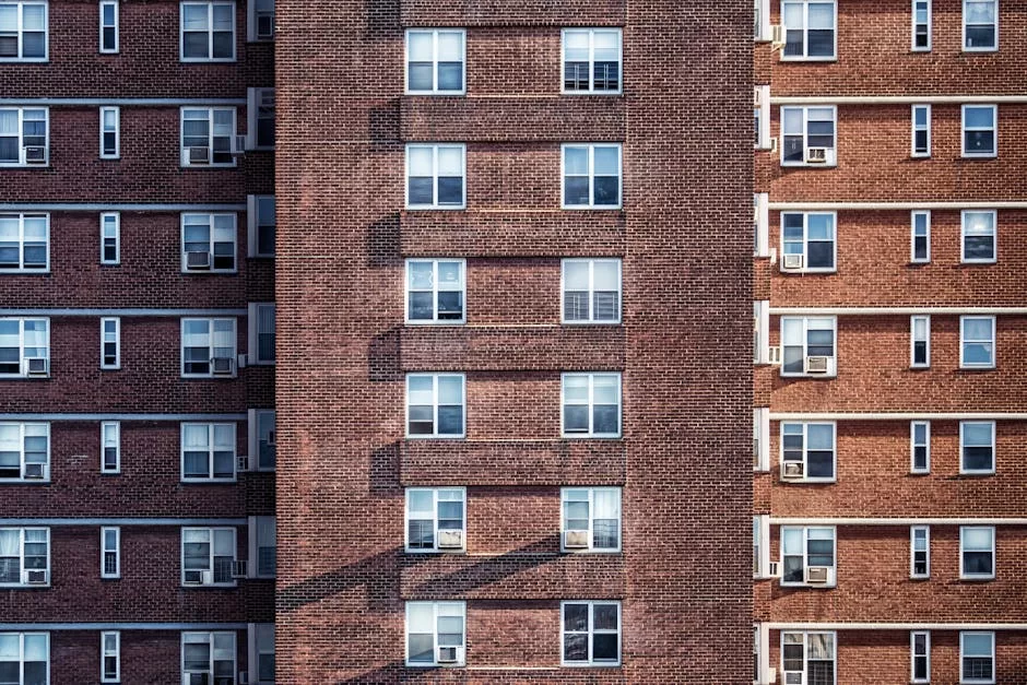 Close-up view of a high-rise brick building facade with multiple windows and air conditioning units.