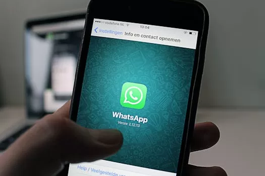 A smartphone displaying the WhatsApp application screen held by a person.