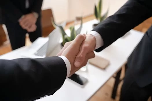 Close-up of a handshake between two professionals in a business setting, symbolizing agreement.