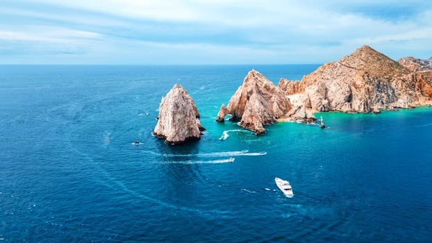 pexels-photo-22912077-22912077 Stunning aerial shot of Cabo San Lucas Arch with vibrant blue ocean and boats in view.