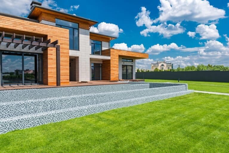 presentación de servicios 13 Exterior of contemporary residential house with panoramic windows glass doors and green lawn in yard on sunny day against blue sky with white clouds