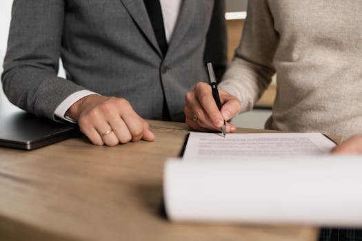 Reglamento de habitaciones 2 Close-up of businessmen signing documents at a wooden table in an office.