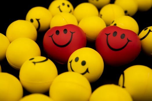 Bright collection of yellow and red smiley face balls and hearts on a dark background.