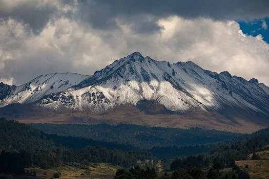 Majestic view of Nevado de Toluca, snow-covered volcano in Mexico under dramatic clouds.