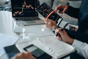Business professionals reviewing financial charts on digital devices in a modern office setting.