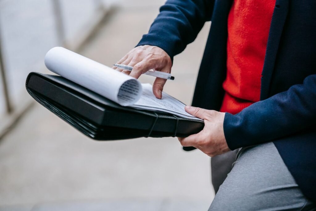 Las 7 Trampas Inmobiliarias Más Comunes en el Estado de México 5 Close-up of a professional person reviewing documents outdoors. Engaged in work with focus on writing materials.